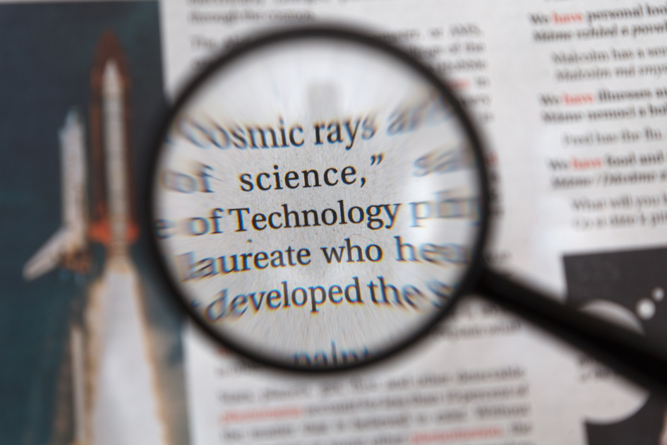 Photo of a magnifying glass showing over a text showing the words science and technology